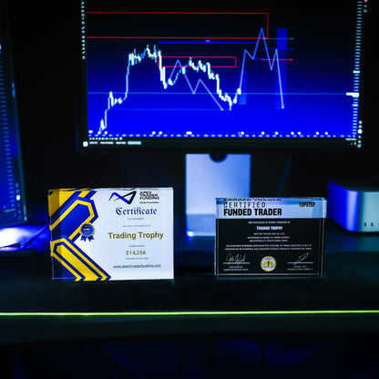 Trading trophies on a desk with a computer screen displaying stock market graphs 